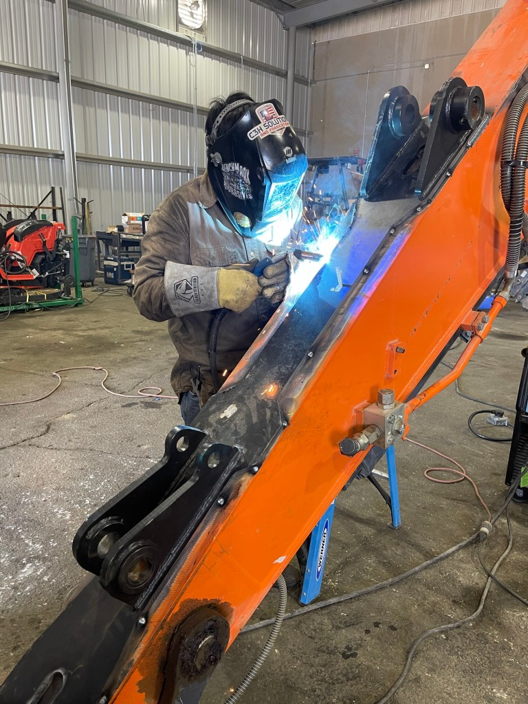 Welder repairing an excavator arm at C3H Solutions