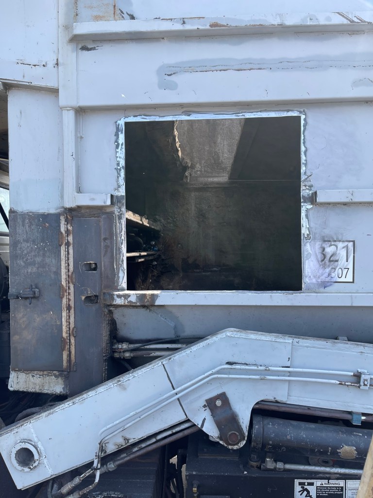 Opened sanitation truck body panel during metal repair